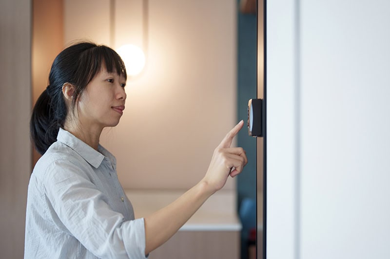 A women changing the thermostat.